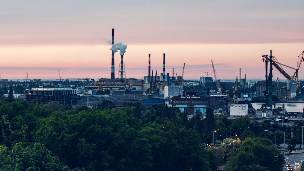 Gdańsk shipyard view with cranes and factories at twilight showcasing industrial vitality.